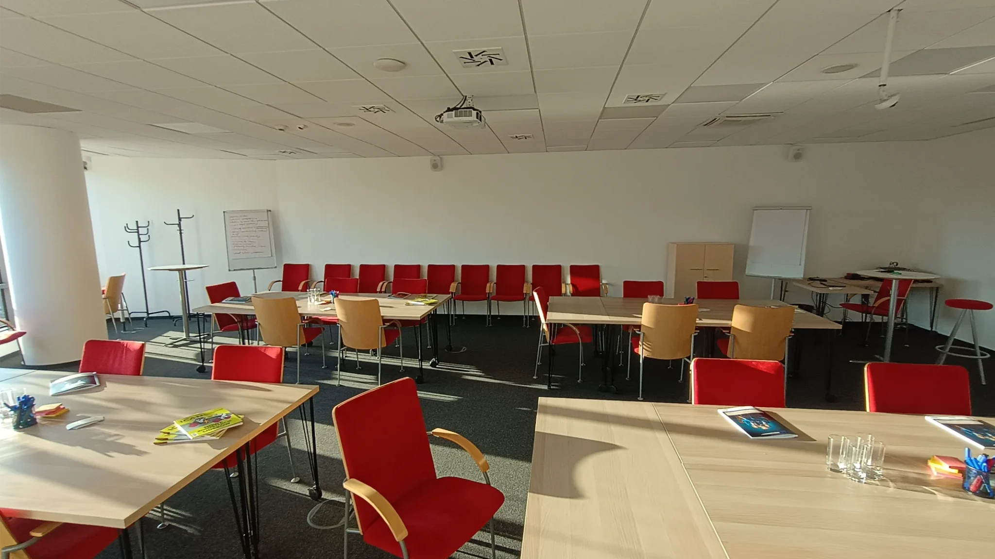 Sala konferencyjna wykończona z sufitami podwieszanymi, gładkimi białymi ścianami, wykładziną dywanową i krzesłami