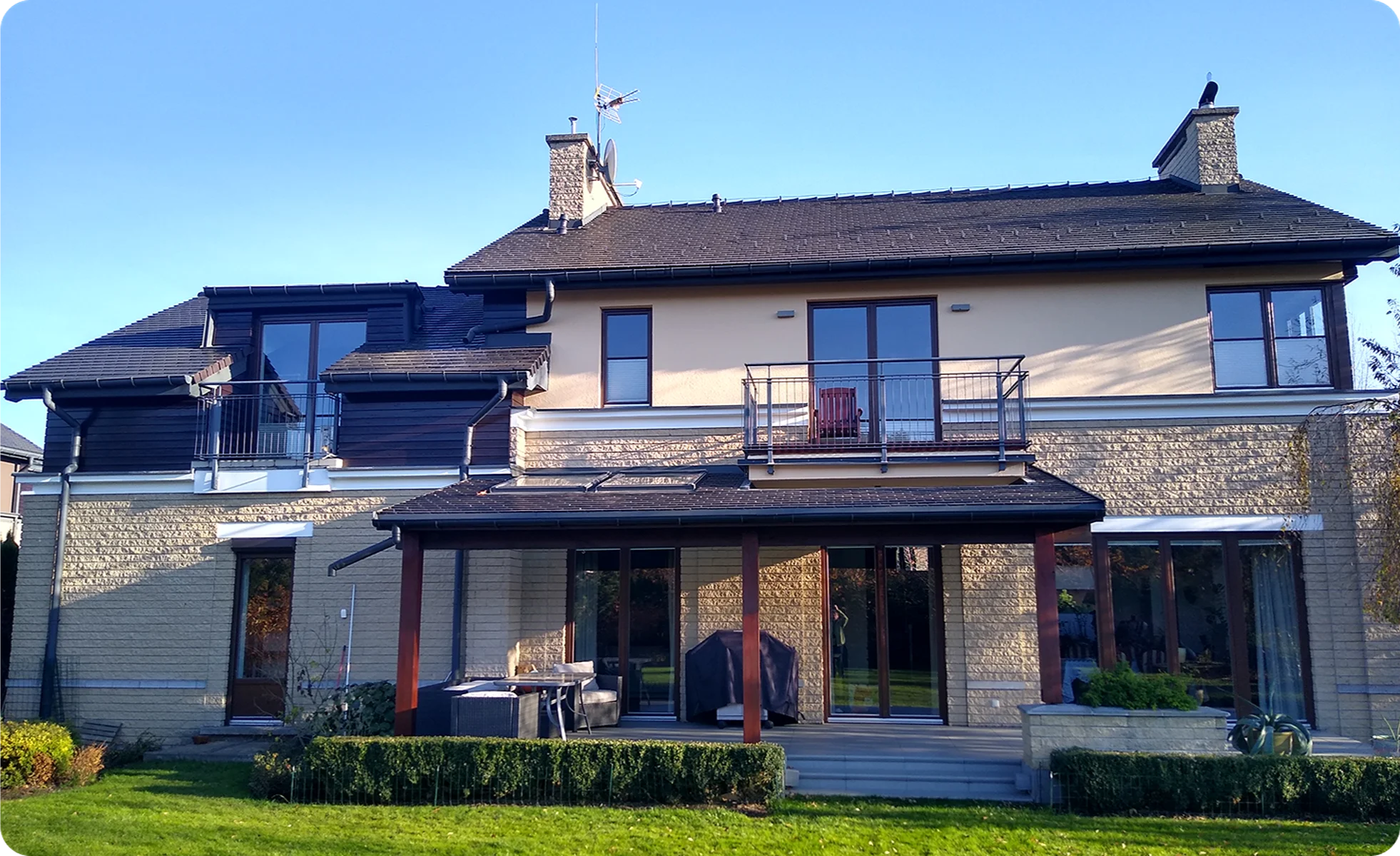 Dwupiętrowy nowoczesny dom z kamienno-ceramiczną elewacją, przeszklonym tarasem i balkonem
