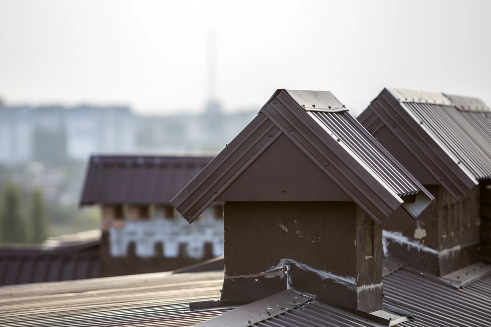 Metalowe pokrycia kominów z obróbką blacharską na dachu budynku