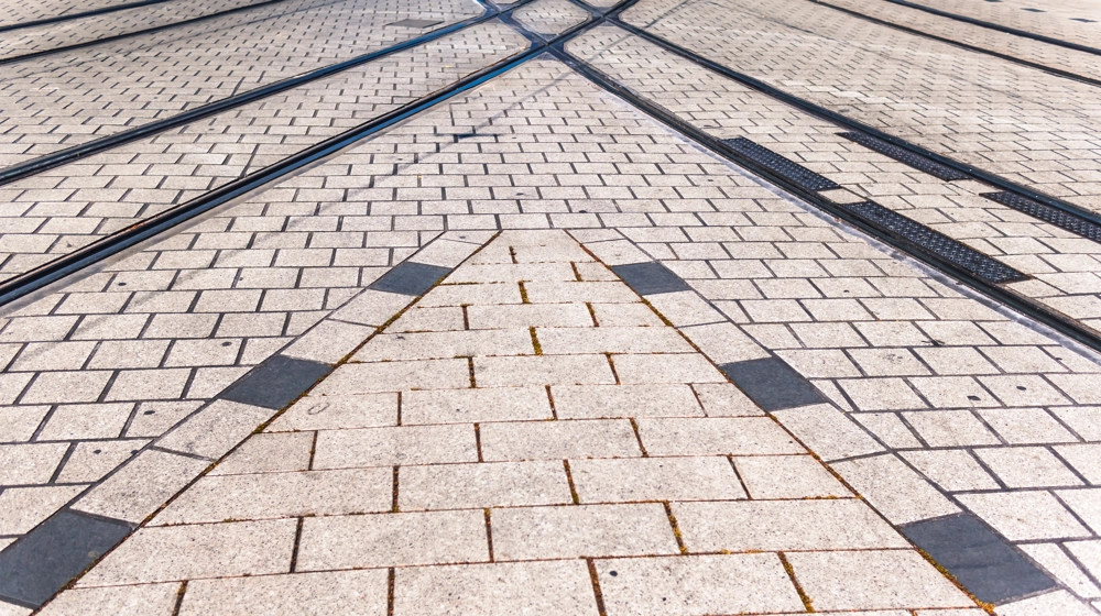 Jasnoszara kostka brukowa ułożona w geometryczny wzór z torami tramwajowymi – Impregnacja kostki brukowej