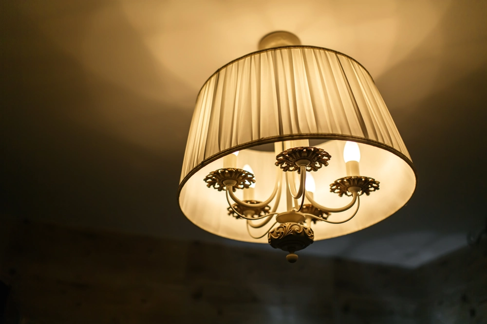 Klasyczna lampa sufitowa z tkaninowym abażurem i ozdobnymi ramionami – oświetlenie