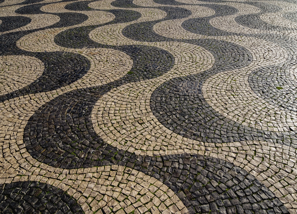 Bruk kamienny ułożony w czarno-biały falisty wzór po myciu kostki brukowej